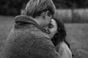 Over-the-shoulder photo of a young couple with their heads together and eyes closed