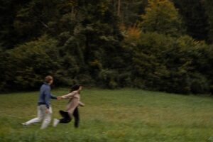 Vintage cinematic motion blur photo of a couple holding hands while walking across a meadow