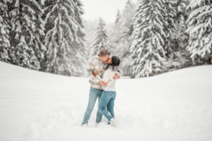 Young couple kissing in a snowy field while snow falls around them