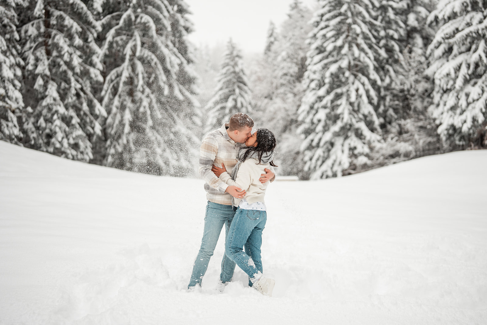Young couple kissing in a snowy field while snow falls around them