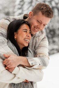Young man embracing his girlfriend from behind while she laughs into nature