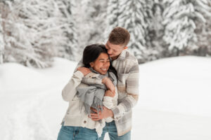 Man embracing his girlfriend from behind while she smiles naturally into nature