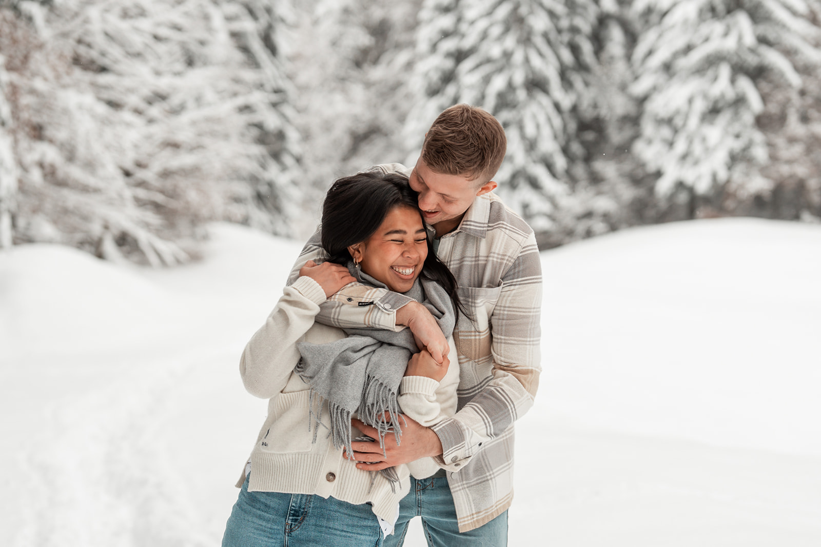 Man embracing his girlfriend from behind while she smiles naturally into nature