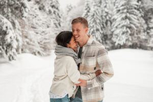Young woman leaning laughing against her partner’s shoulder while both laugh
