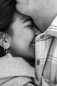 Black-and-white close-up of a Thai woman smiling while leaning against her partner