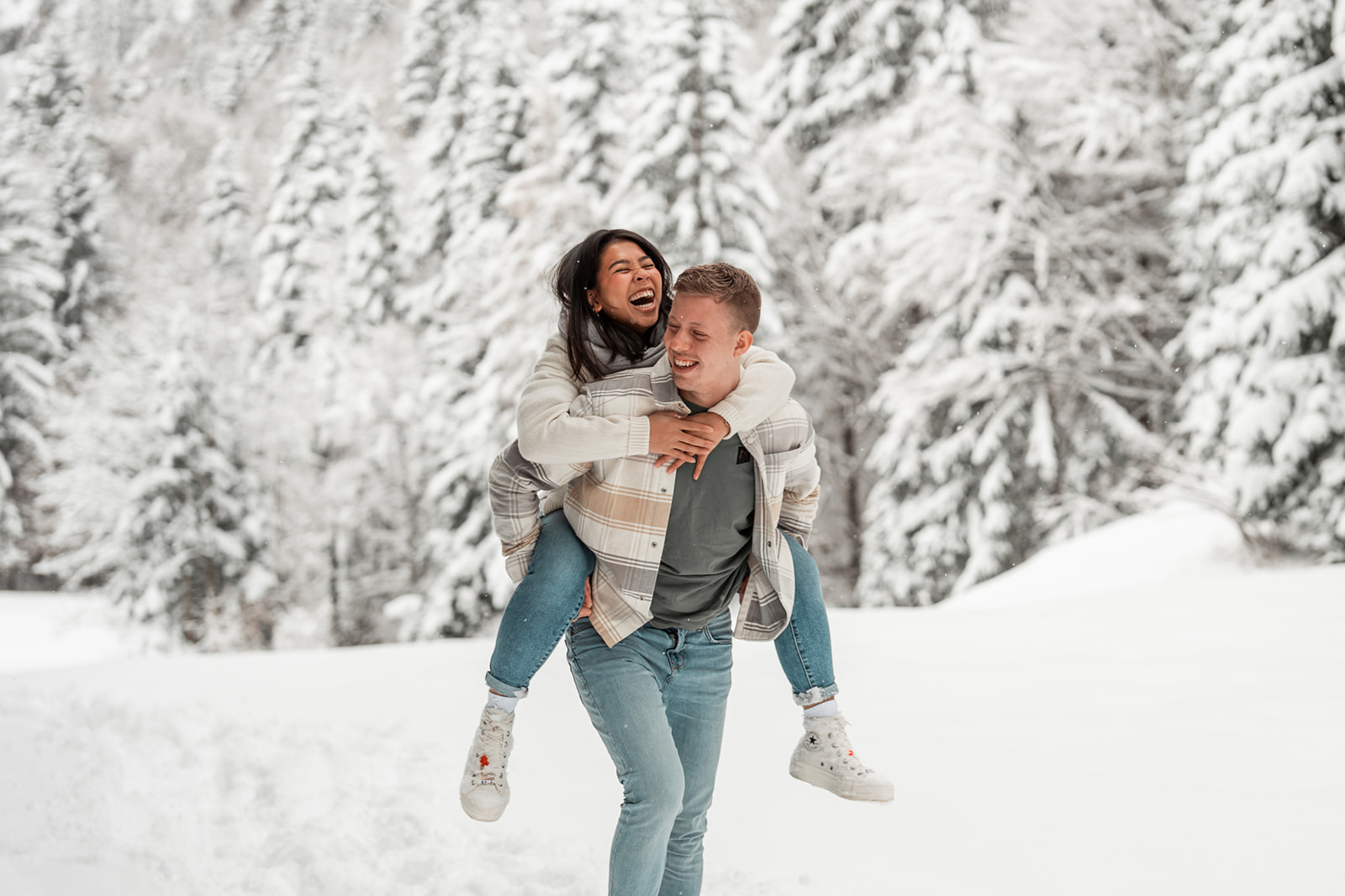 Piggyback photo of a young couple with the woman laughing joyfully on his back