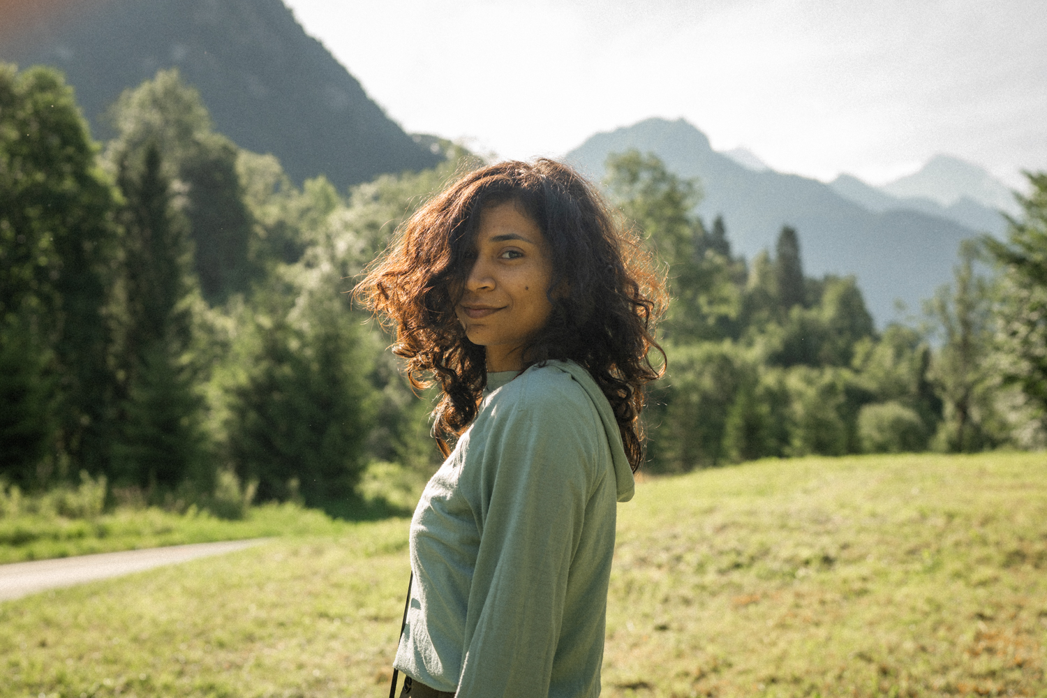 Vintage cinematic photo of a young Indian woman smiling at the camera in the Swiss mountains