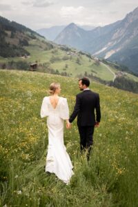 Wedding couple standing hand in hand in a flower meadow while looking at each other