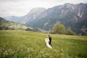 Wedding couple walking through a flower meadow between the mountains of East Tyrol while looking ahead
