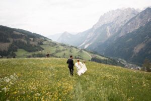 Wedding couple walking through a blooming meadow between the mountains of East Tyrol