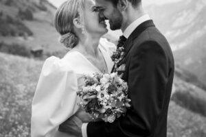 Black-and-white close-up of a wedding couple leaning in for a kiss while smiling warmly