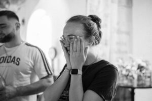 Black-and-white photo of the bride holding her hands to her face with joy