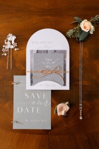 Flat lay featuring the invitation, jewelry, and floral details