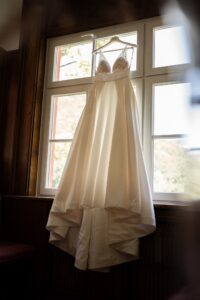 Wedding dress hanging in front of a window, photographed from a low angle