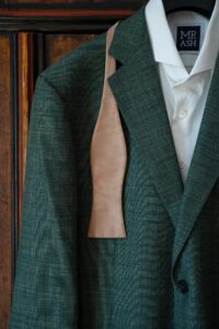 Close-up of a beige bow tie draped over the suit jacket