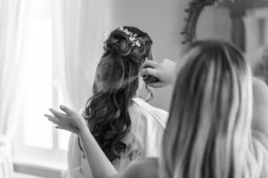 Black-and-white photo of the bride’s hairstyle as hairspray is applied