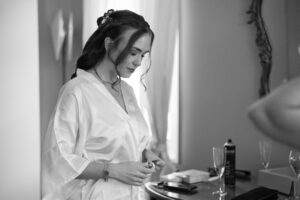 Black-and-white photo of the fully styled bride in a silk robe