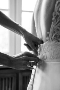 Black-and-white close-up of hands fastening the wedding dress