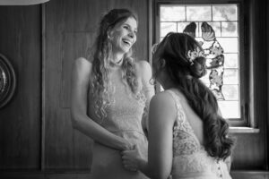 Black-and-white photo of the maid of honor laughing warmly across from the bride
