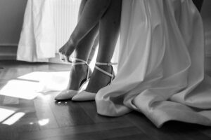 Black-and-white close-up of the bride’s shoes being fastened