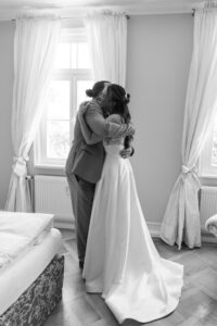 Embrace between the bride and her father during their first look by the window