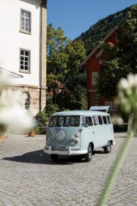 A light blue VW bus parked in a courtyard