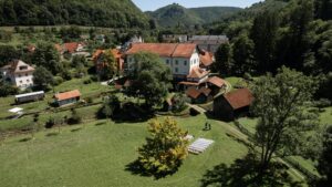 Drone photo of the ceremony location on a green meadow with a large tree and the Künkele Mill in the background