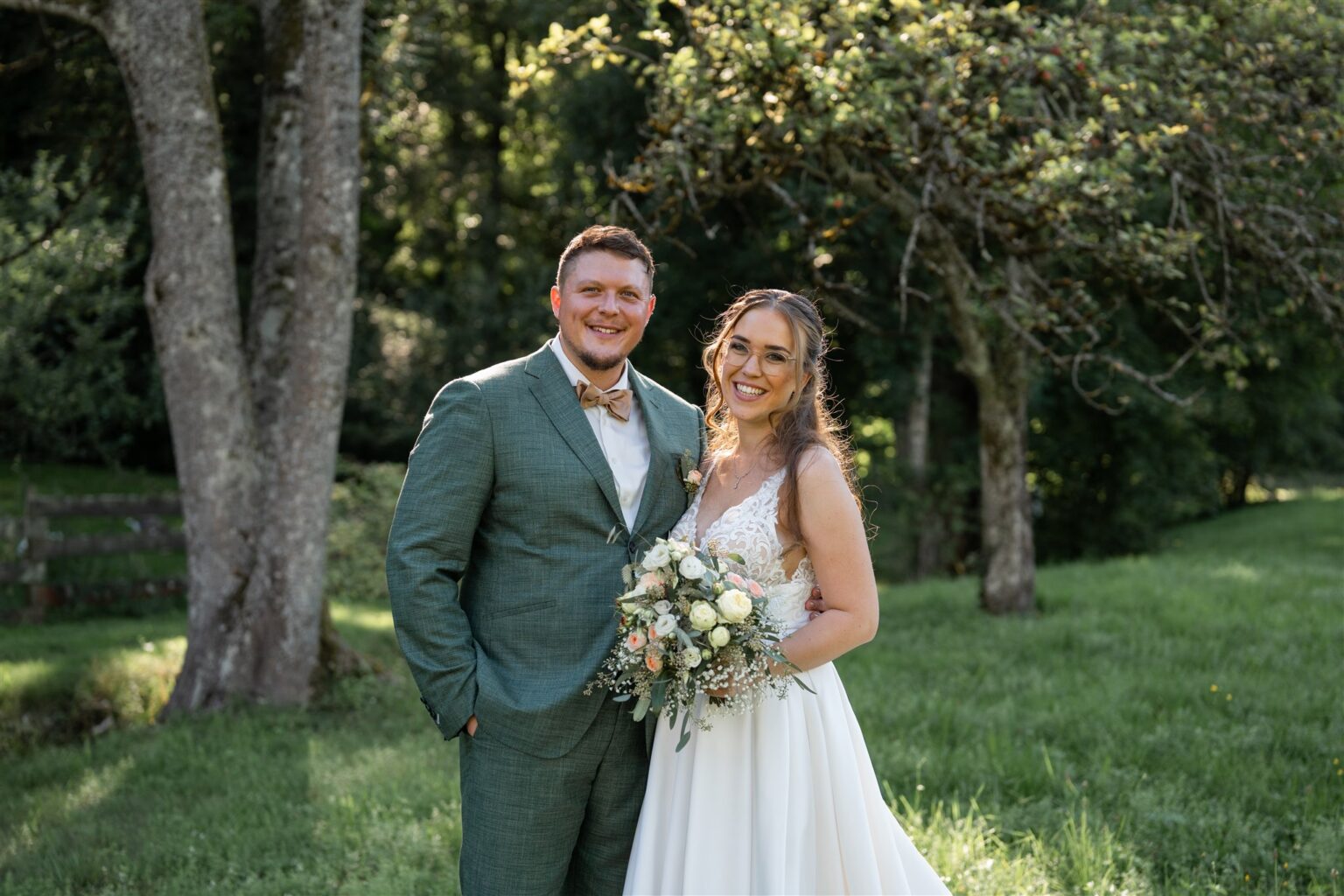 Young wedding couple standing arm in arm and smiling at the camera