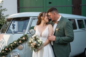 Mid-range portrait of the wedding couple in front of a VW T2 bus