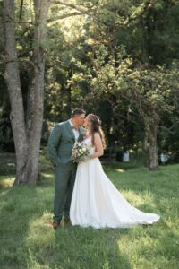 Bride and groom kiss in a meadow bathed in golden evening light