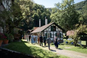 Wedding guests walking past a barn on their way to the ceremony