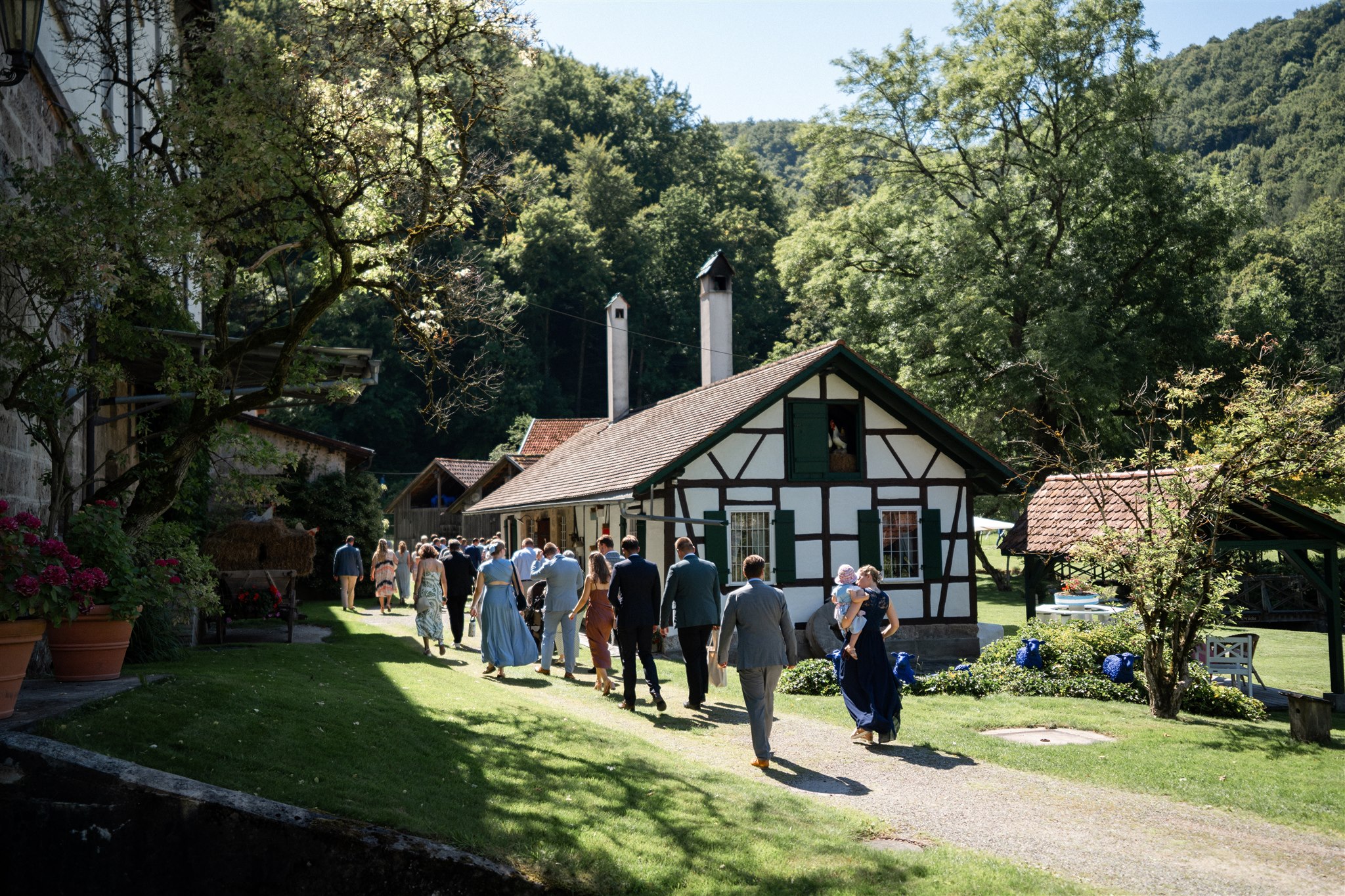 Wedding guests walking past a barn on their way to the ceremony