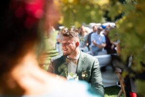 Over-the-shoulder shot of the officiant as the groom laughs warmly