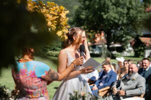 The bride holds her vows and laughs behind her hand
