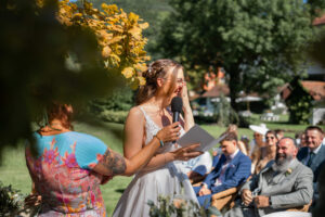 The bride holds her vows and laughs behind her hand