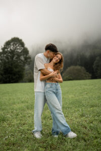 Young woman embraced from behind by her fiancé while smiling into nature