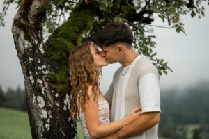 Couple kissing beneath a tree while embracing each other