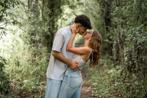 Couple passionately kissing beneath an arch of trees and leaves