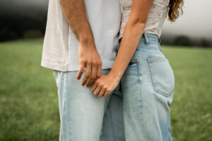 Close-up of a couple holding hands with focus on the engagement ring