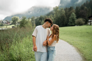 Young couple walking hand in hand along a path while smiling at each other