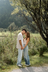 Young couple standing hand in hand by the roadside with their heads leaning together