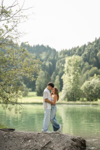 Young couple standing by a reflective lakeshore just before a kiss