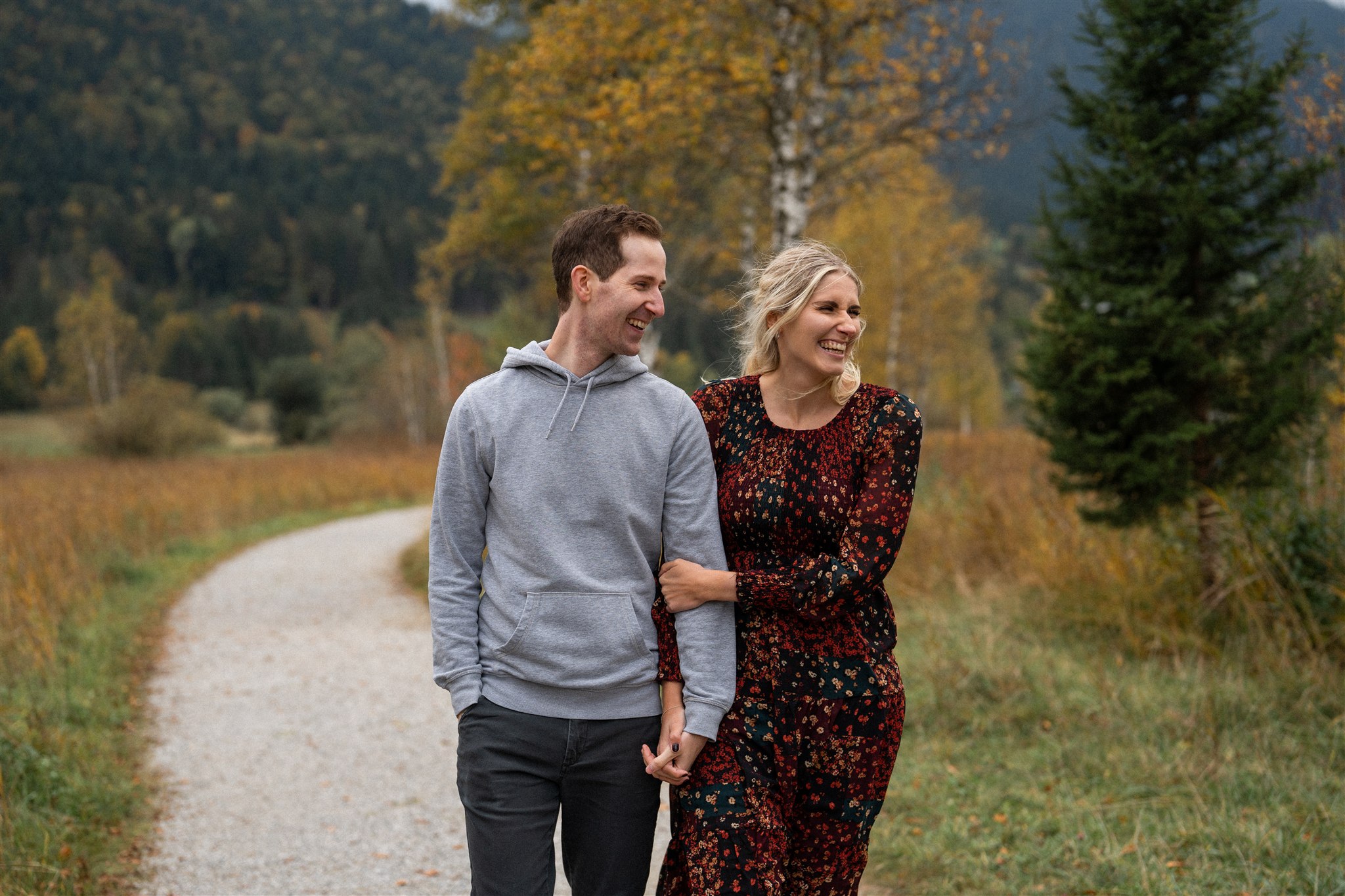 Young engaged couple walking and laughing together on a path in autumn nature