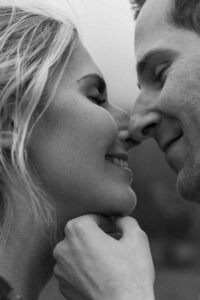 Black-and-white close-up of a loving couple with closed eyes and gentle smiles