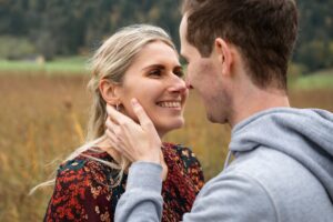 Over-the-shoulder photo of a man holding his fiancée’s face while she smiles lovingly at him