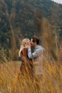 Young couple kissing between tall orange grass