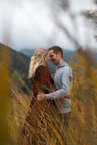 Young couple between orange grass with their heads leaning together