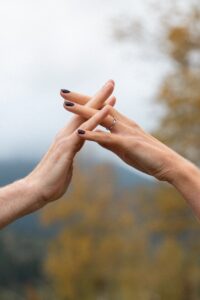 Close-up of intertwined hands in front of autumn trees and mountains