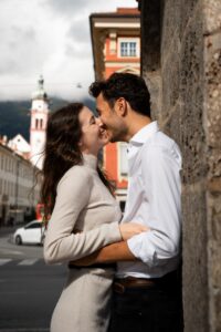 Young couple leaning against a column while almost kissing in front of the city backdrop