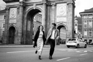 Black-and-white photo of a couple holding hands with slight motion blur in front of Innsbruck’s Triumphal Arch